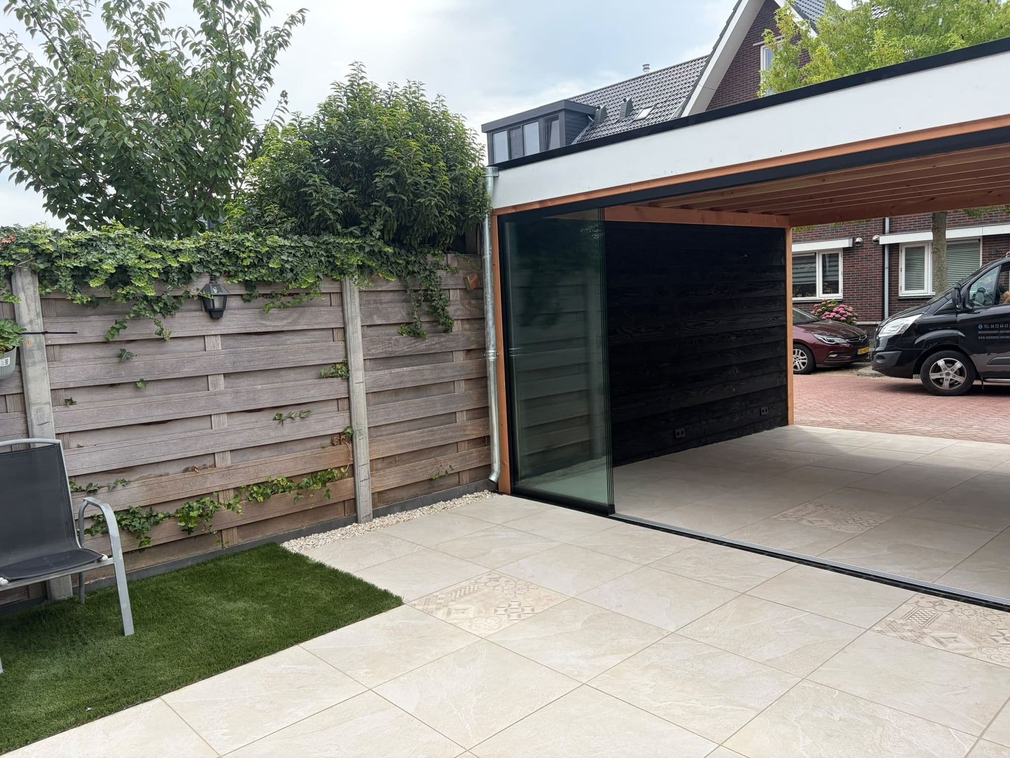 Douglas overkapping met glazen schuifwand aan een keramisch terras