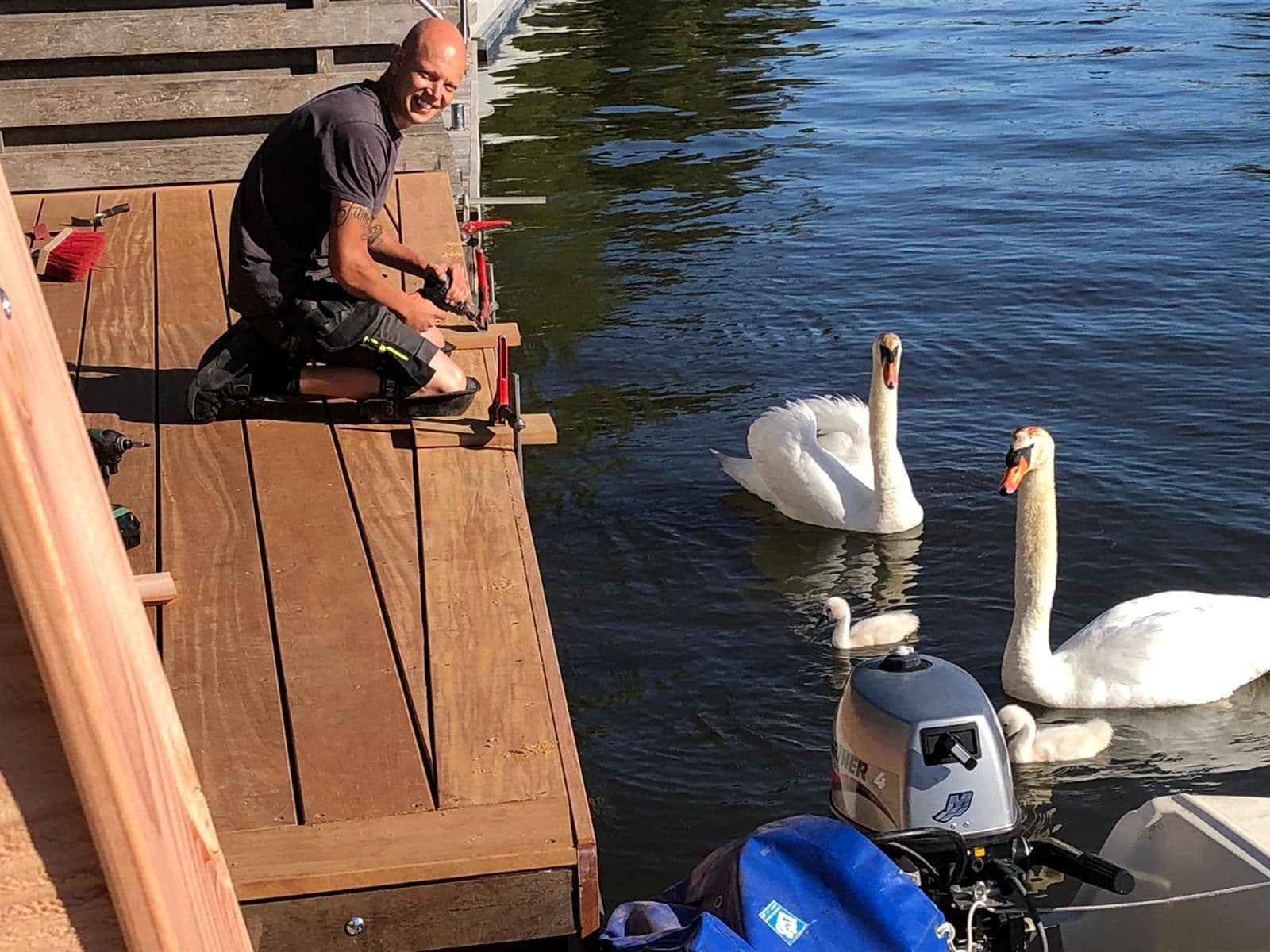 Michiel Hogervorst aan het werk aan een steiger, met zwanen in het water